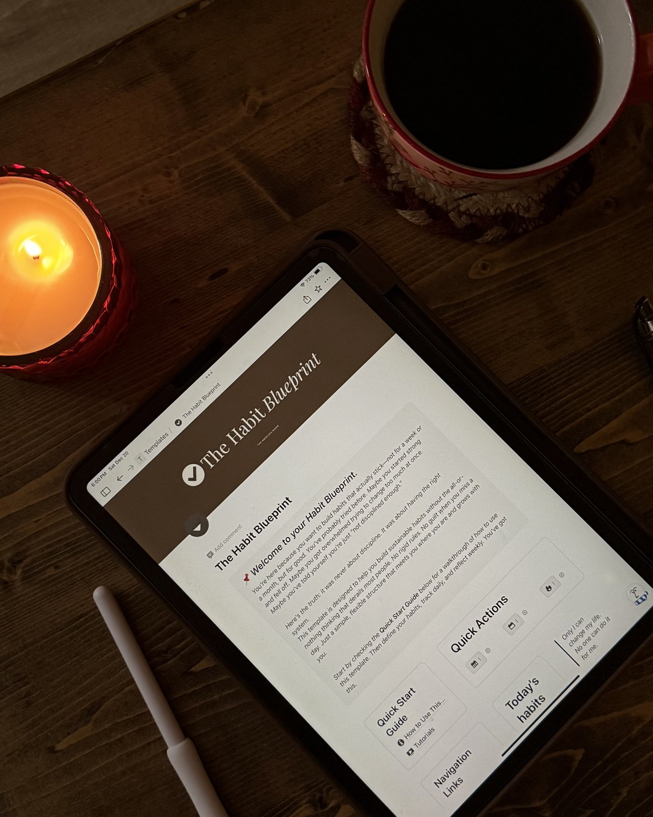 The Habit Blueprint open on a tablet beside a candle and a cup of coffee